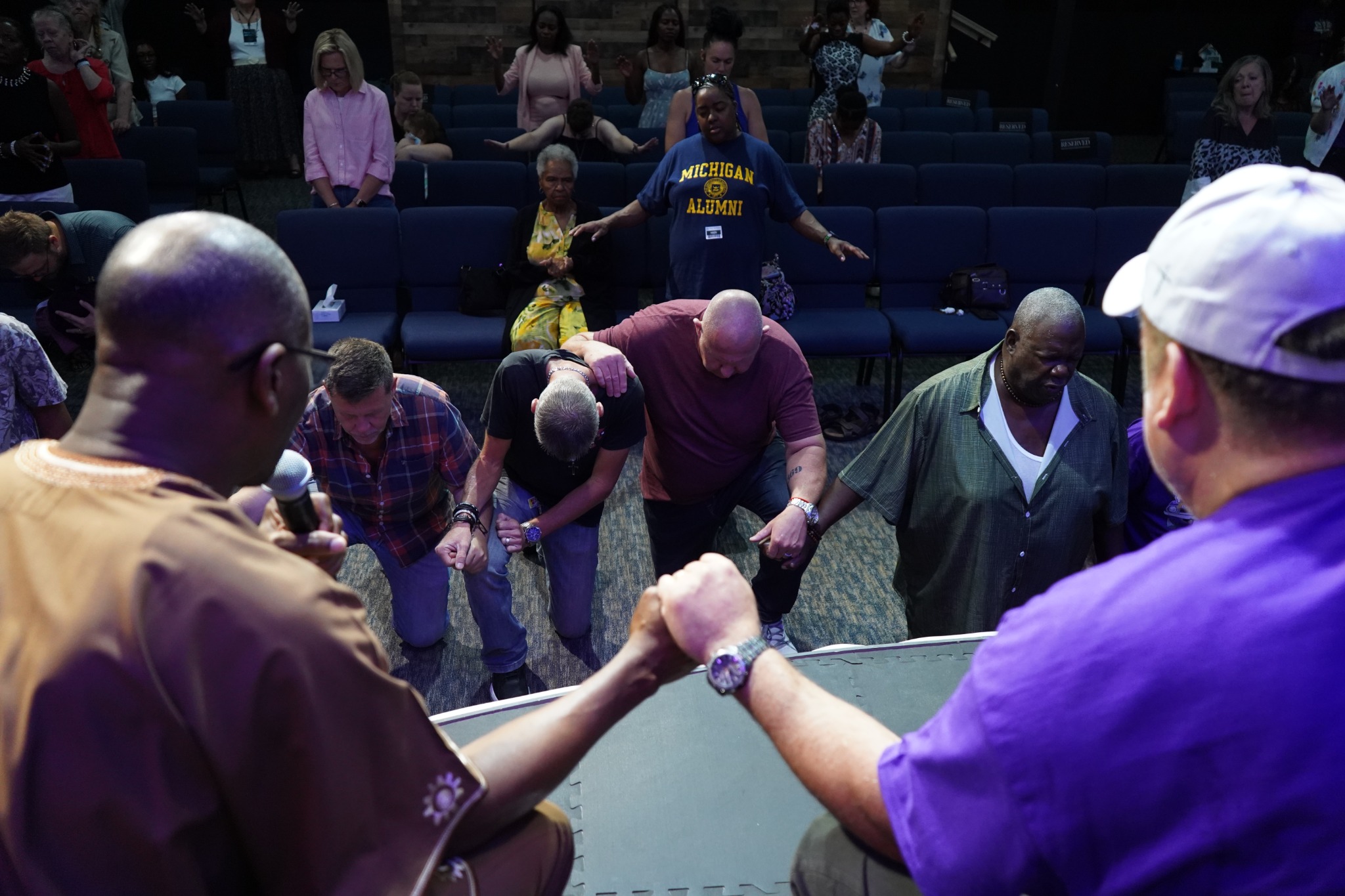 People holding hands and praying near the sanctuary stage.