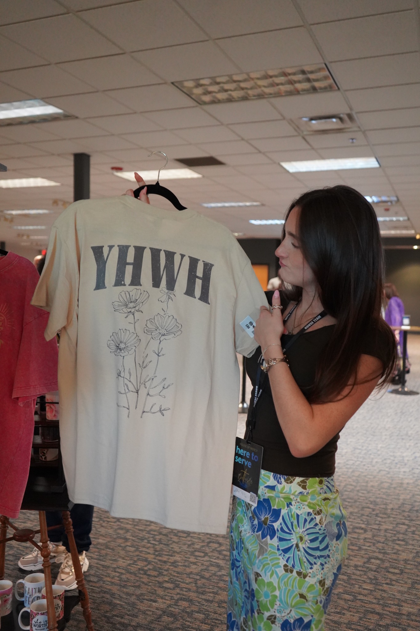 A young adult holding a faith-themed shirt at church.